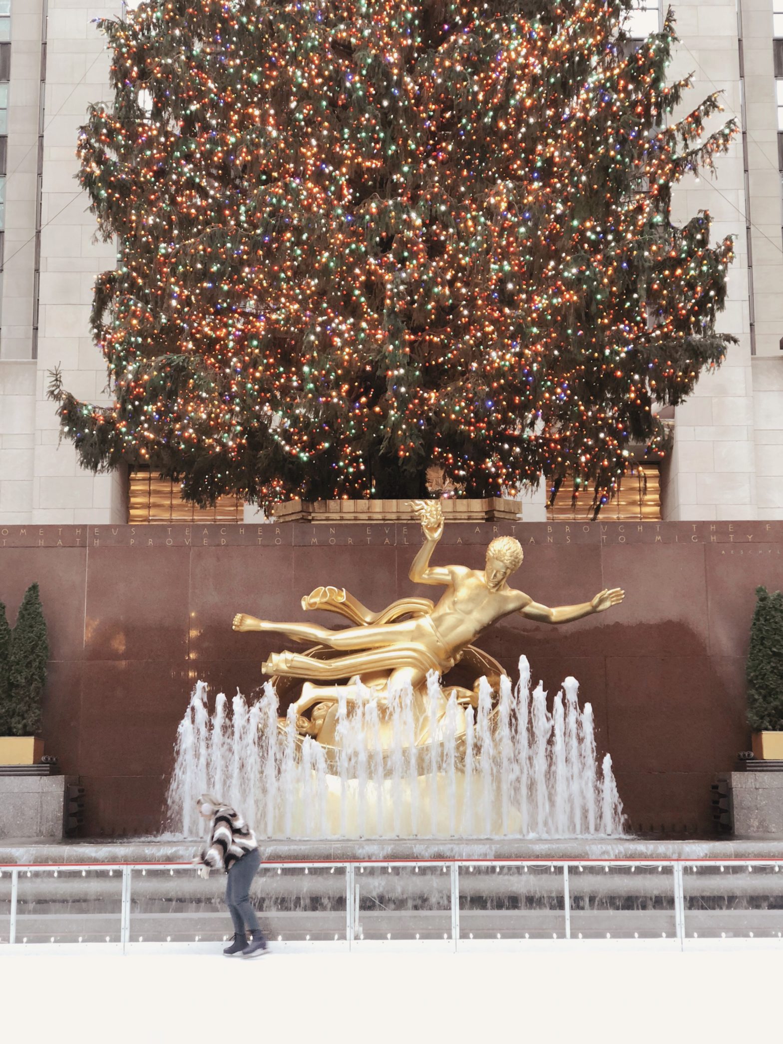 ice skating in front of the Rockefeller Tree and golden statue and fountain in New York