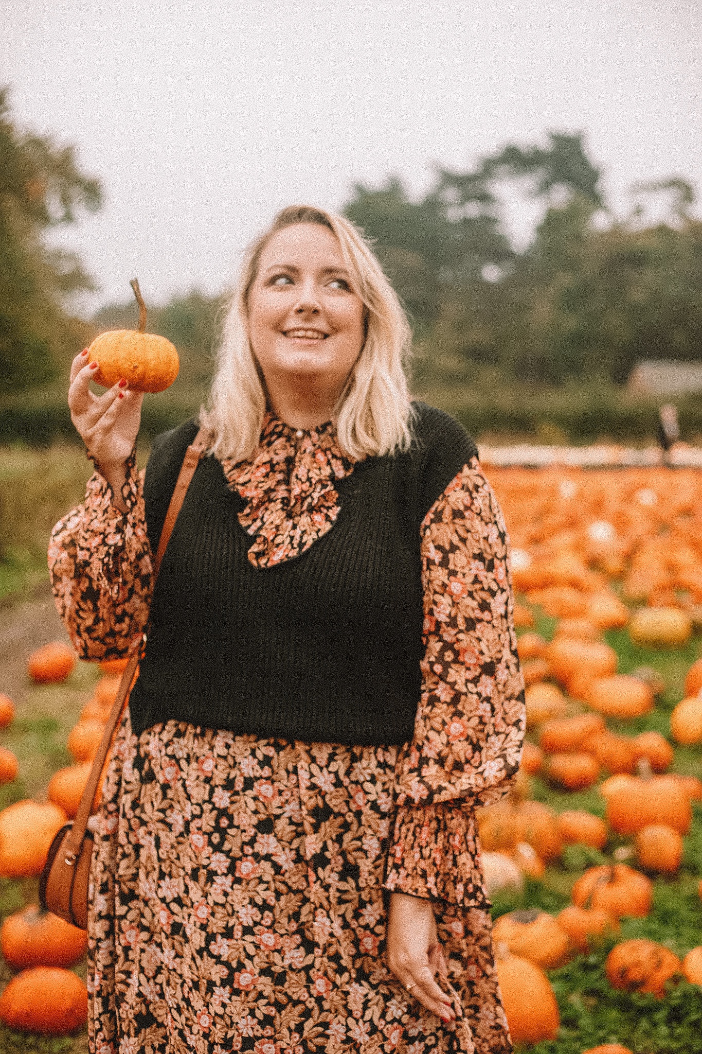 Lucy stood in a pumpkin field holding a pumpkin
