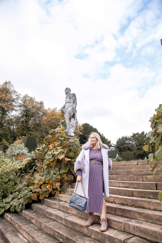 Lucy stood on steps in a lilac coat and boots