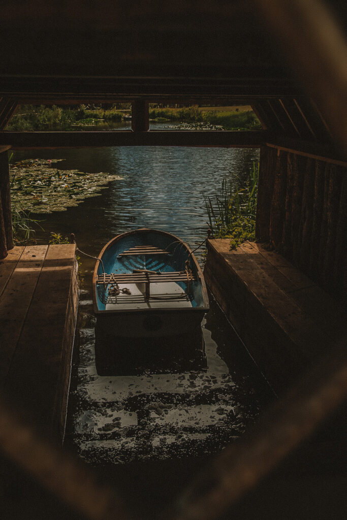 A boat sits on the pond in the boathouse