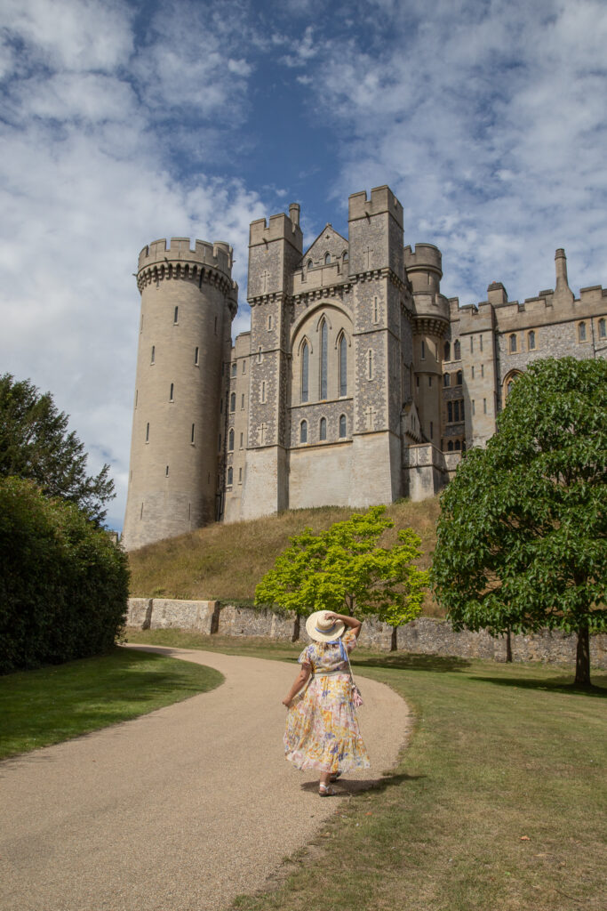 Lucy in her fave neon rose maxi dress and a straw hat looking up to arundel castle