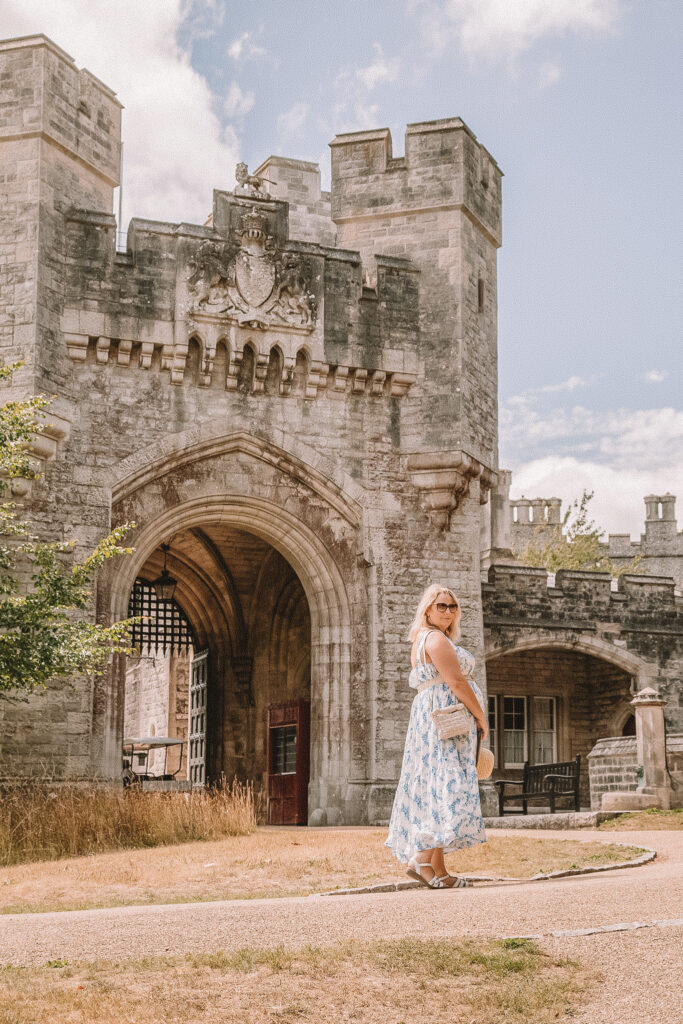 lucy is stood in front of a castle gate in a blue and white lrona luxe x in the style maxi dress
