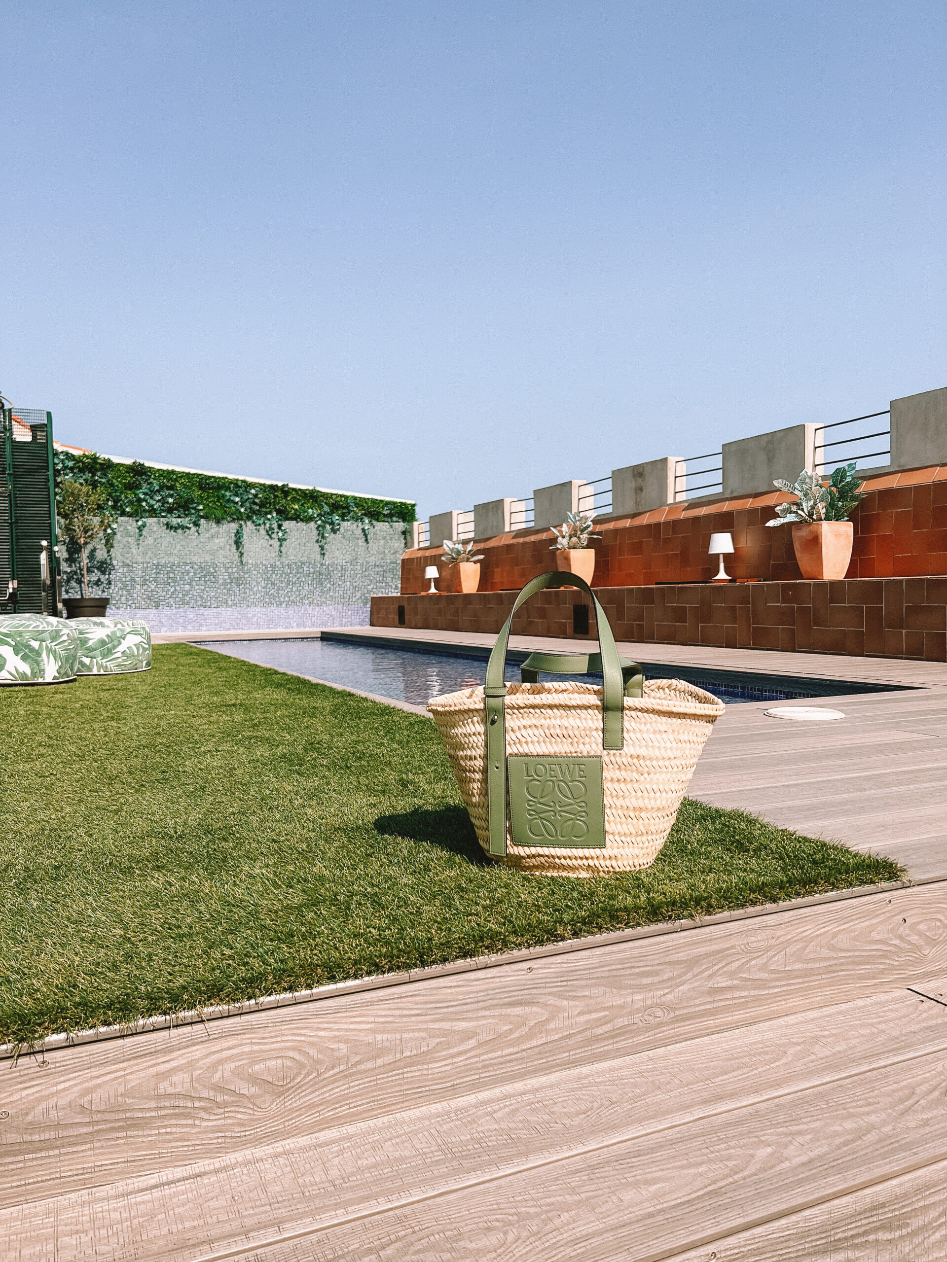 paulas ibiza Loewe basket bag on the faux grass with the dipping pool behind it on the rooftop
