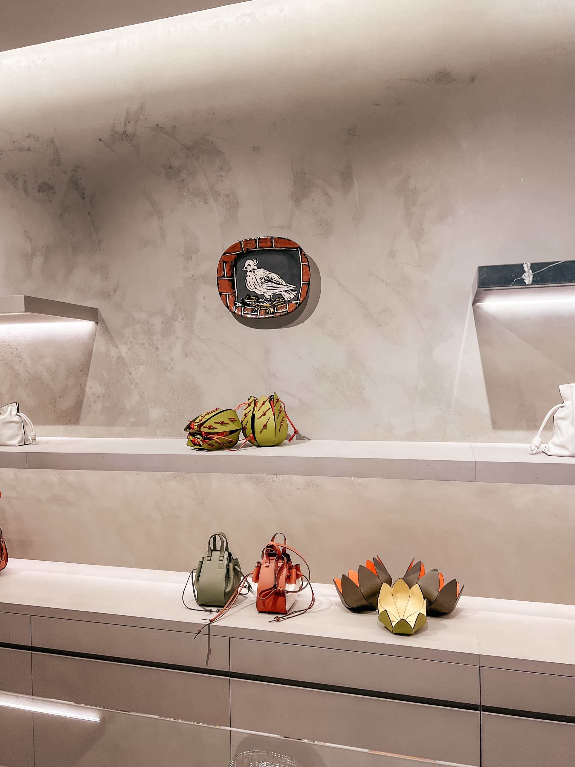 picasso pottery on the wall with Loewe leather goods on shelves around it