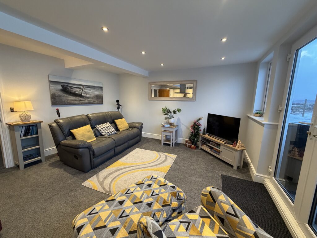 the living area of the apartment with a sofa, comfy chair and footstool 