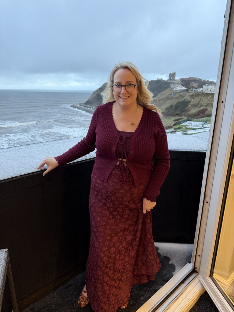 lucy stood on the balcony dressed in burgundy 